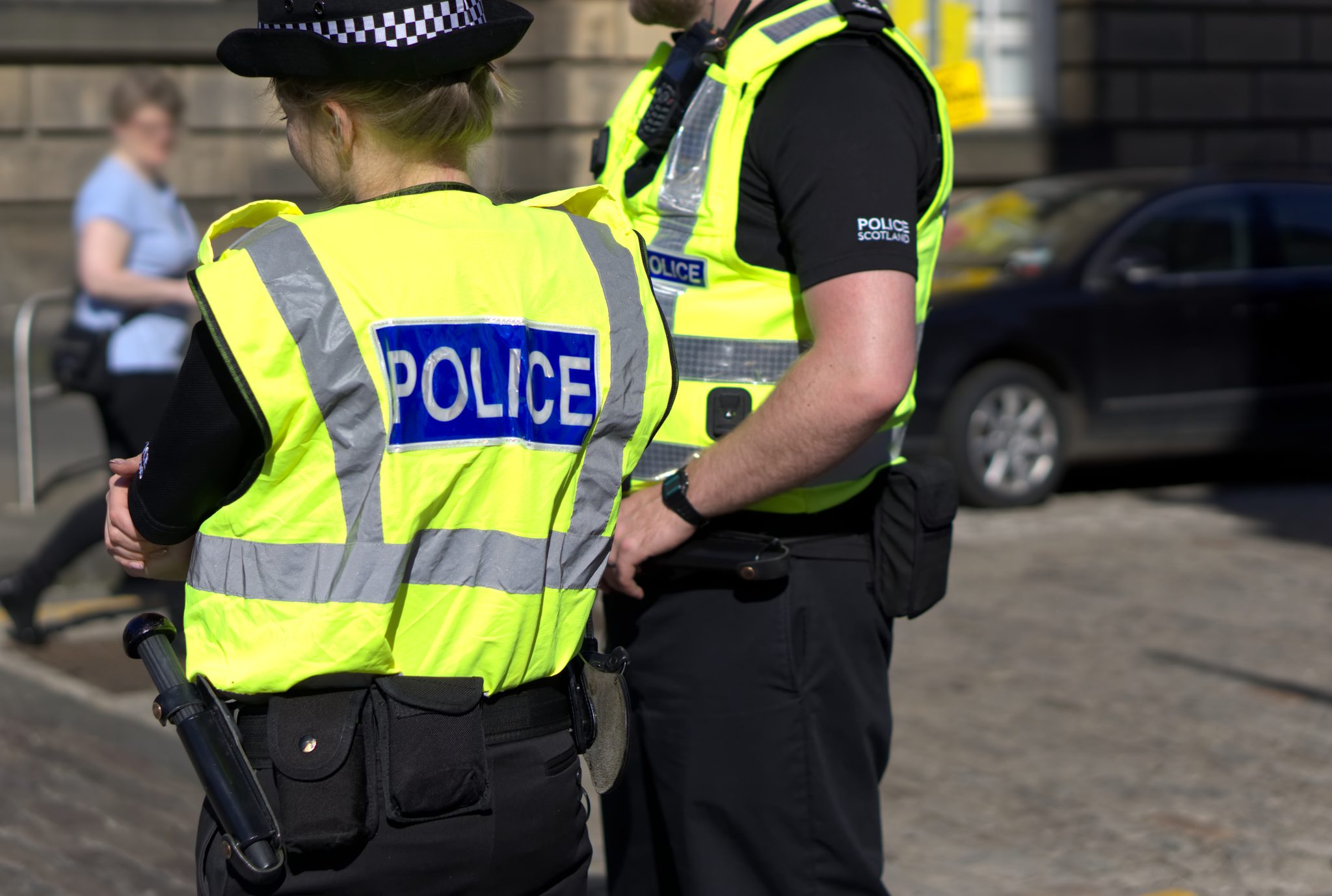 A male and a female police officers wearing high vis vests with the word "Police" across the back